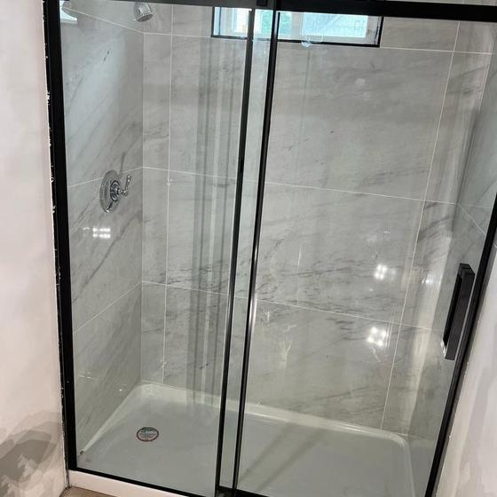 Frameless glass shower door installed on a tiled base