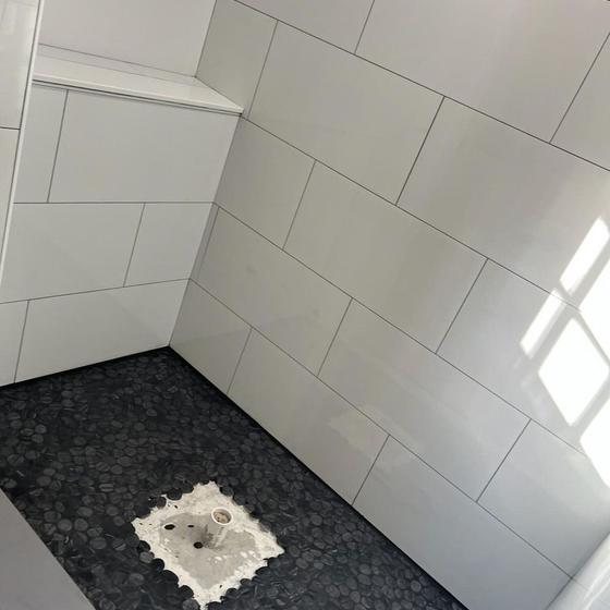 Finished pebble shower floor against white wall tile
