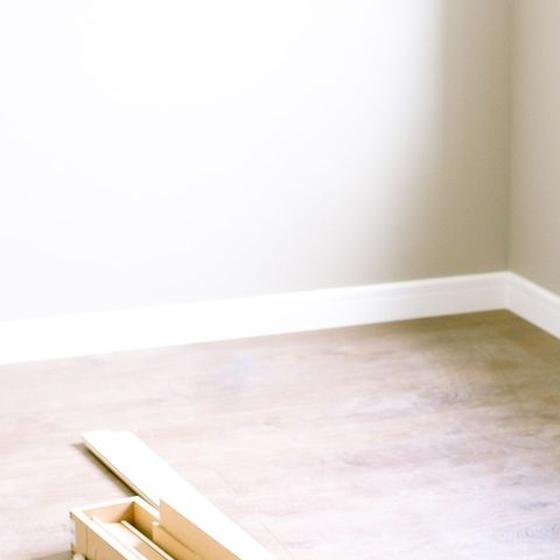 New painted baseboard run along two walls with raw trim offcuts on the floor