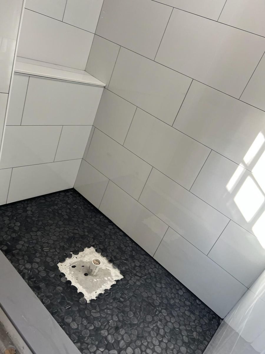Pebble mosaic shower floor against white wall tile
